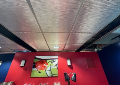 Red feature wall with a framed sports photograph, two wall sconces, and a pair of adjustable black lamps in a blue-walled room.