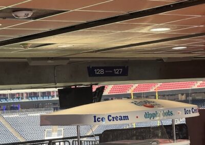 Dippin’ Dots ice cream cart under a white umbrella in a stadium concourse, with empty seating and ceiling tiles in the background.